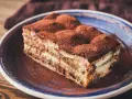 Pyszne tiramisu ze skyrem, posypane kakao, na niebieskim talerzu. Idealne na deser.