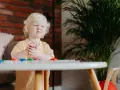 Mały chłopiec z miną wyrażającą bunt 4 latka objawy, trzyma w rączkach fioletową zabawkę.
