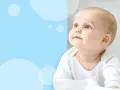 Słodka kaszka na twarzy niemowlaka, który z zaciekawieniem patrzy w górę.