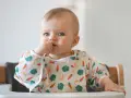 Niebieskooki maluch w śliniaczku z marchewkami i bananami, kiedy dziecko widzi kolory.