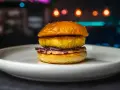 Apetyczny burger z halloumi, z chrupiącą panierką i kolorową surówką, na białym talerzu.