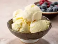 Pyszne, kremowe lody waniliowe w miseczce. Idealne na deser, pokazują, jak się robi lody. W tle owoce.