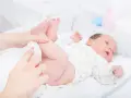 Rączka rodzica zmienia pieluchę noworodkowi. Czy to przed czy po karmieniu, ważne by maluszek był czysty i szczęśliwy.