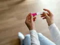 Dłonie trzymające test ciążowy, który może wskazać pierwsze objawy ciąży.