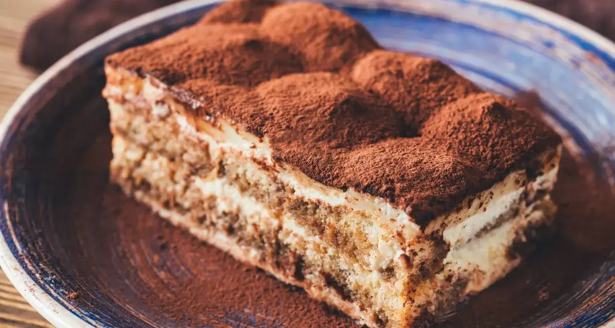 Pyszne tiramisu ze skyrem, posypane kakao, na niebieskim talerzu. Idealne na deser.