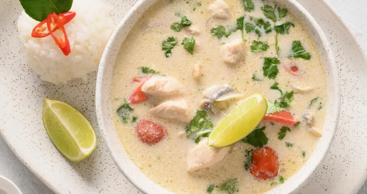 Aromatyczna tajska zupa z kurczakiem, podana z ryżem, limonką i chili.