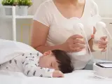 Mama odciąga pokarm 7-5-3, podczas gdy jej dziecko śpi spokojnie.