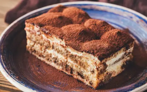 Pyszne tiramisu ze skyrem, posypane kakao, na niebieskim talerzu. Idealne na deser.