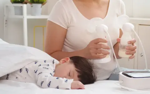 Mama odciąga pokarm 7-5-3, podczas gdy jej dziecko śpi spokojnie.