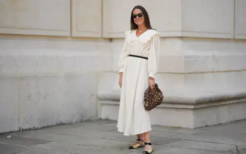 Kobieta w kremowej sukience z falbankowym kołnierzem, czarnym paskiem i panterkową kopertówką. Uosobienie swobodnej elegancji smart casual damski.