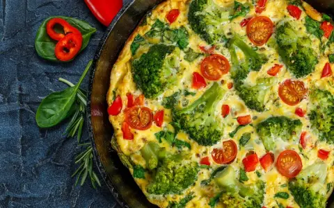 Pyszny omlet z warzywami: brokuły, pomidorki koktajlowe i papryka w złocistym jajku.