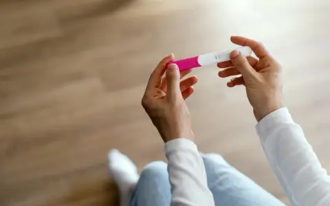 Dłonie trzymające test ciążowy, który może wskazać pierwsze objawy ciąży.