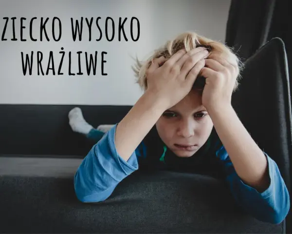 Chłopiec z rękami na głowie, wyrażający smutek. Tekst "Dziecko wysoko wrażliwe" sugeruje, że to objawy dziecka wysoko wrażliwego.