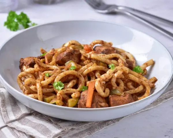 Pyszne udon z kurczakiem i warzywami, posypane świeżą natką pietruszki.