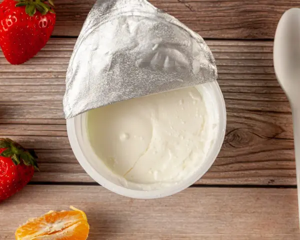 Jogurt naturalny właściwości: kremowy, gładki, z owocami i łyżeczką na drewnianym tle. Idealny na zdrowy deser.