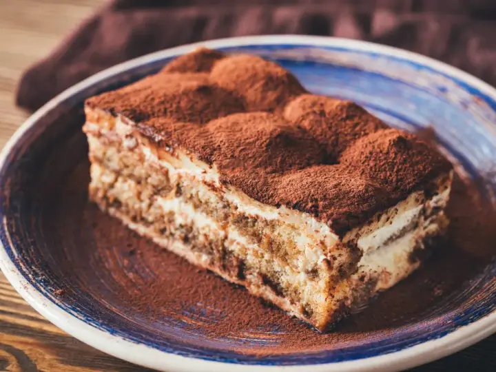 Pyszne tiramisu ze skyrem, posypane kakao, na niebieskim talerzu. Idealne na deser.