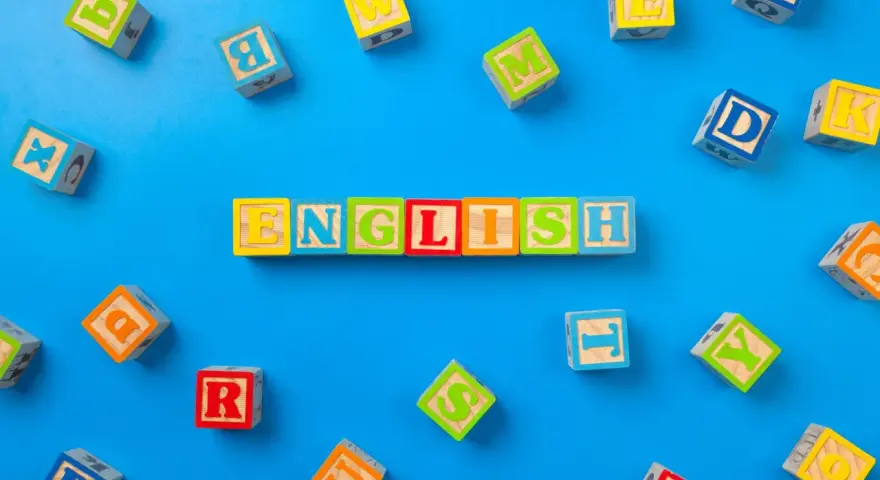 Kolorowe klocki z literami układają się w napis "ENGLISH". To świetny sposób, jak nauczyć dziecko angielskiego przez zabawę.