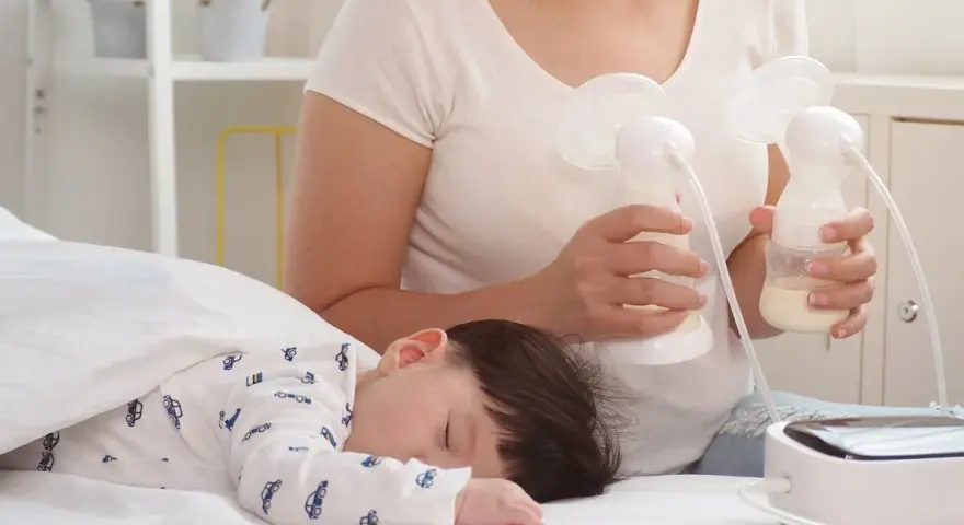 Mama odciąga pokarm 7-5-3, podczas gdy jej dziecko śpi spokojnie.