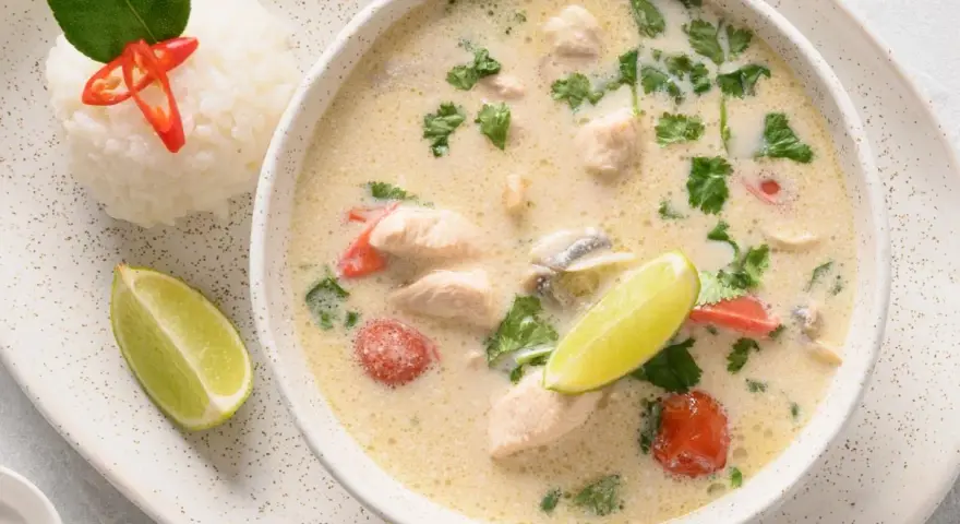 Aromatyczna tajska zupa z kurczakiem, podana z ryżem, limonką i chili.