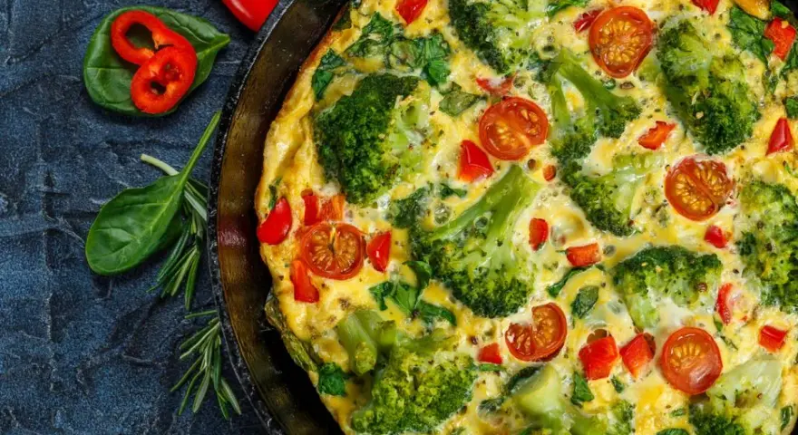 Pyszny omlet z warzywami: brokuły, pomidorki koktajlowe i papryka w złocistym jajku.