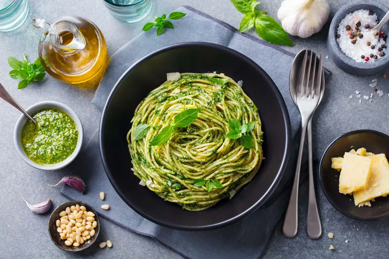 Pyszny, lekkostrawny obiad bez mięsa: spaghetti z pesto, świeżą bazylią, orzeszkami pinii i parmezanem.