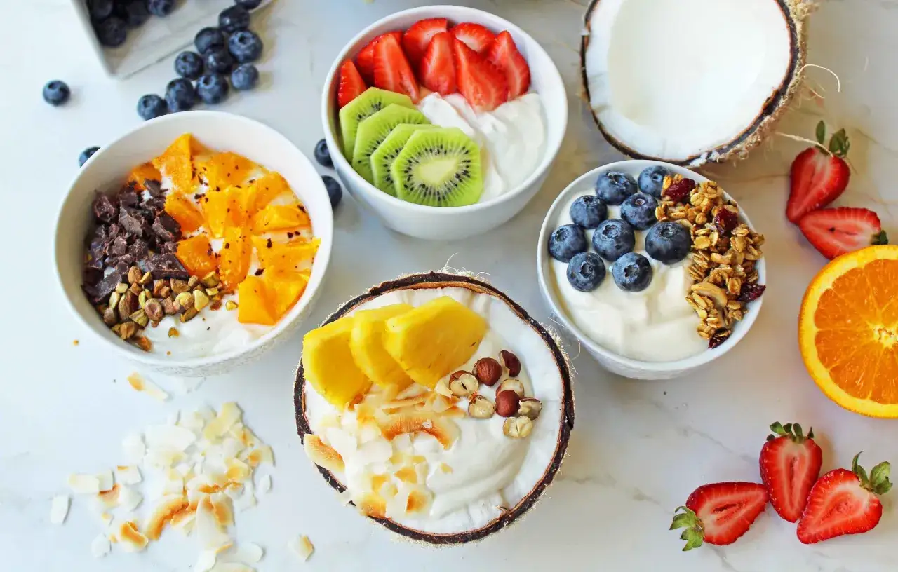 Zdrowe śniadanie: jogurt z owocami (truskawki, kiwi, pomarańcze, ananas, borówki), orzechami i granolą. Idealne na dieta bez cukru.