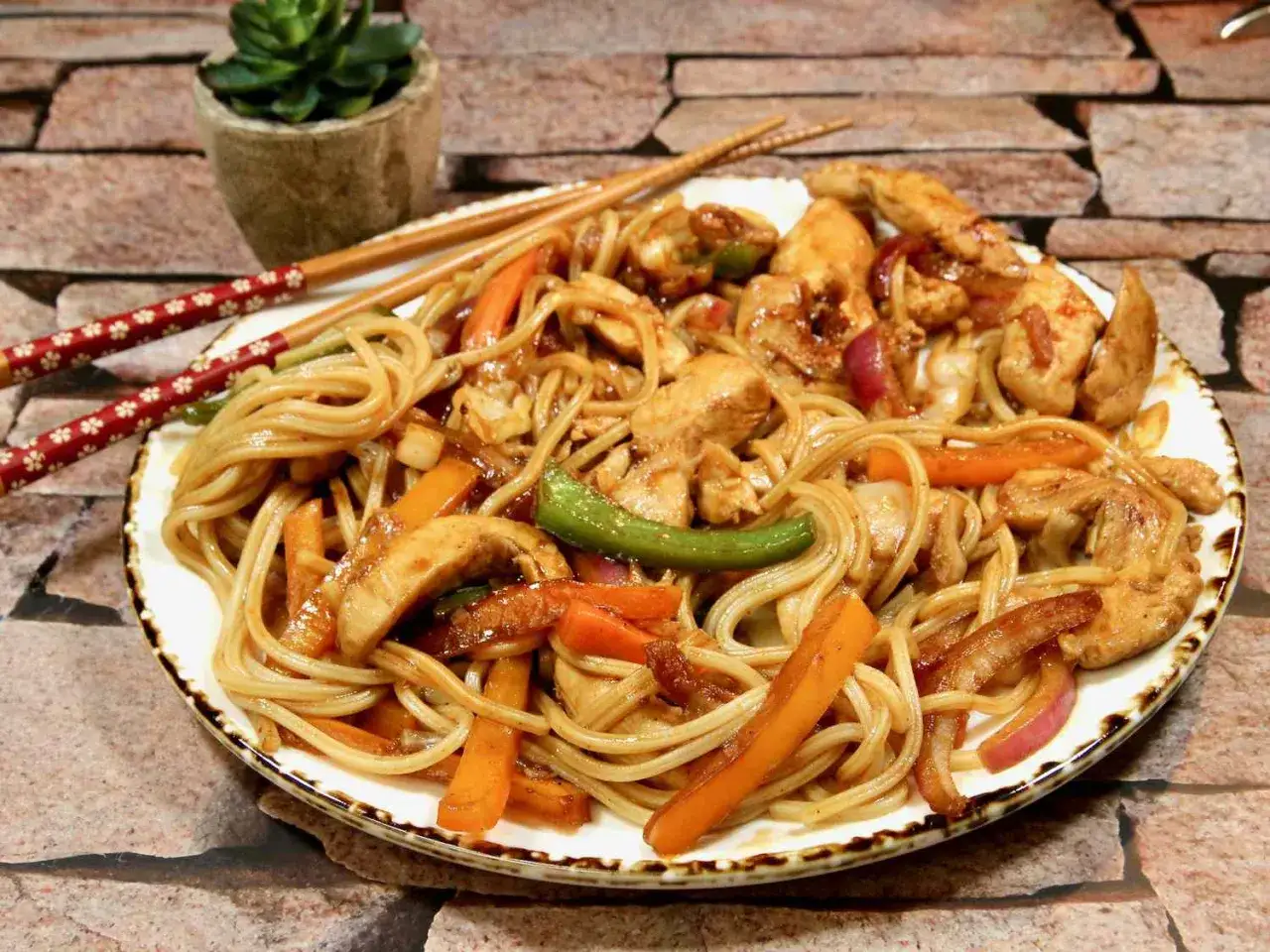 Pyszne udon z kurczakiem i warzywami, podane z pałeczkami.